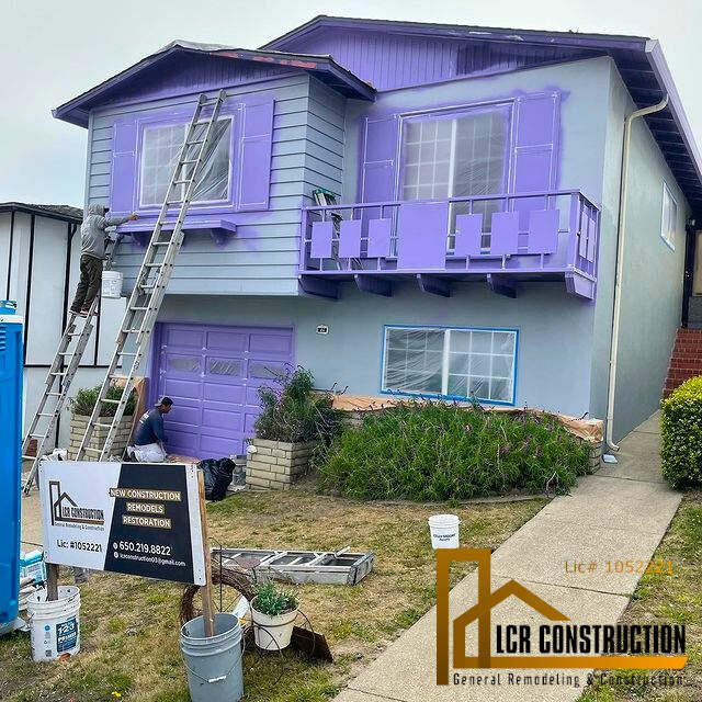 An exterior remodeling of a house with purple siding and a ladder.