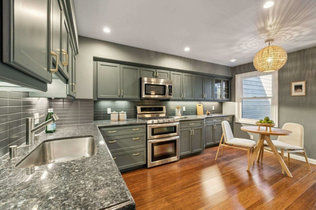 Modern kitchen with dark cabinets, stainless steel appliances, and a small dining area with a round table and chairs.