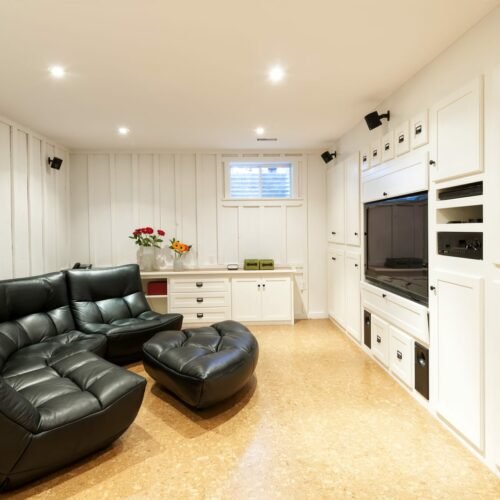 A living room with a black leather couch and tv, offering comfortable seating for entertainment services.